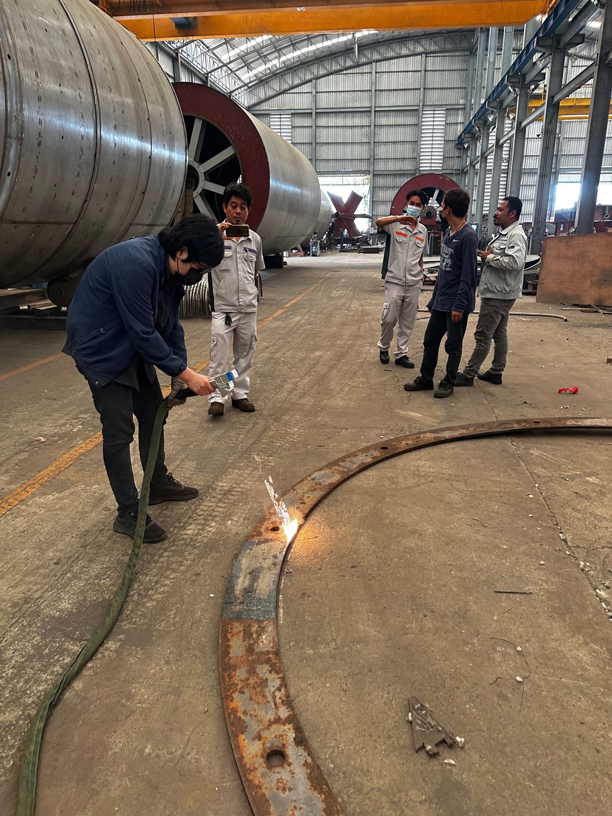 On-site laser cleaning demo on a steel flange at the Service Center, customers observing